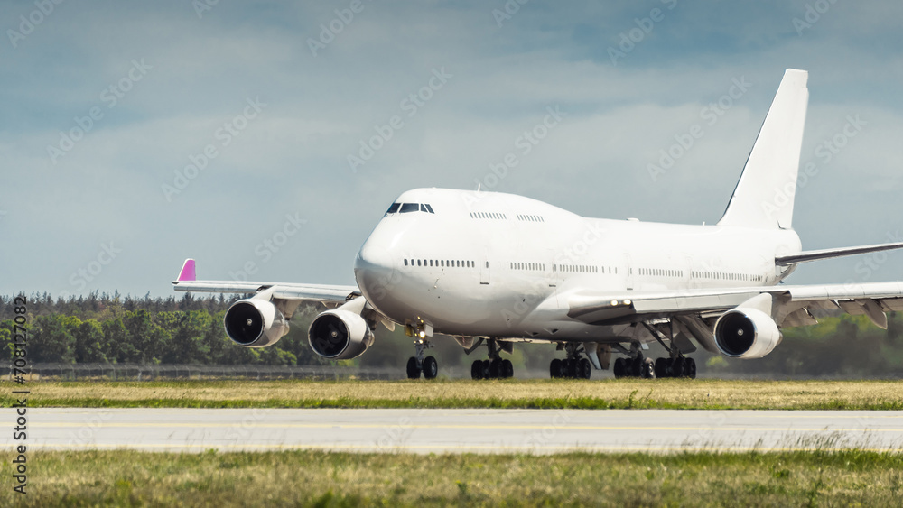 Huge white passenger aircraft accelerating for take-off along the runway, hot exhaust coming out of the engine and distorts the visibility. Front three quarter view of two-storey jumbo jet on a ground Huge white passenger aircraft accelerating for take-off along the runway, hot exhaust coming out of the engine and distorts the visibility. Front three quarter view of two-storey jumbo jet on a ground