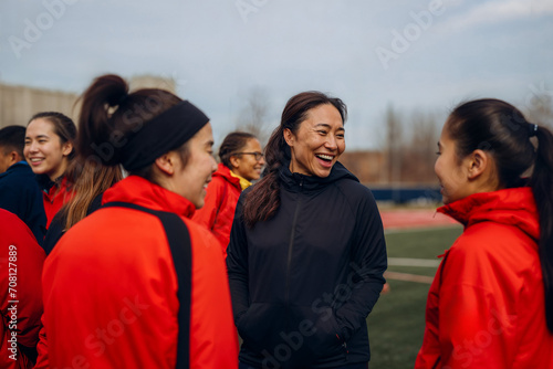 Female coach laughing with women's soccer team. Generative AI image photo