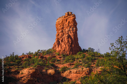 This scenic landscape image shows an epic red rock formation with a blue sky in the background. 
