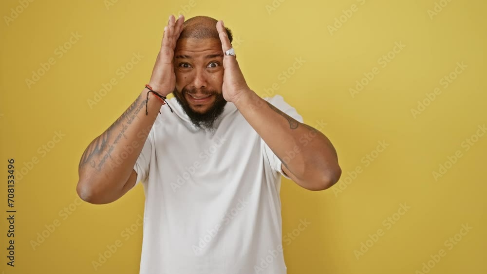 Surprised african american man covering face with hand, peeking through fingers in shock, standing isolated on yellow background Surprised african american man covering face with hand, peeking through fingers in shock, standing isolated on yellow background