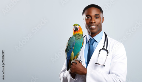 a young veterinarian black african  man in a white coat holds a exotic parrot in her hands on a white background with space for text. Concept: veterinary clinics, love for animals, poster, banner, 