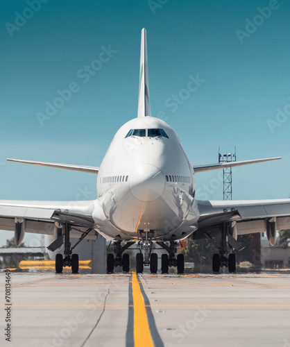 Huge white passenger aircraft taxiing, hot exhaust coming out of the engine and distorts the visibility. Frontal close-up view of two-storey jumbo jet on the ground on a sunny day. 