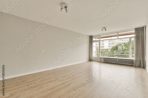 Spacious empty room with large window and hardwood floor photo