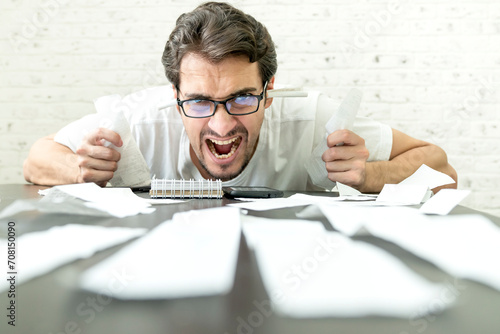 Close up of unhappy man sitting at the table, stressed and confused by calculate expense from invoice or bills, have no money to pay mortgage or loan. High prices and spending money concept photo