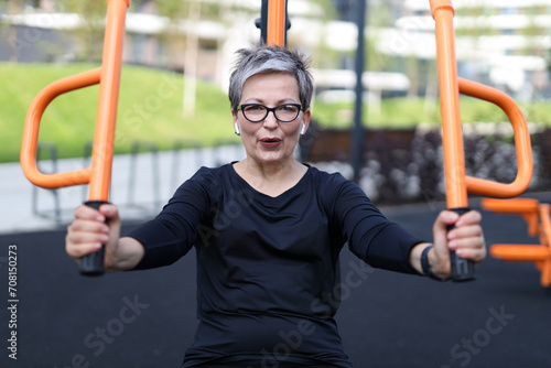 Senior woman finds relaxation and exercise in outdoor gym, embodying a healthy and happy lifestyle.