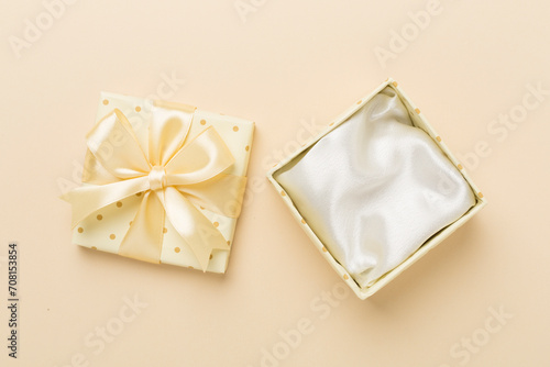 Beige open gift box on color background, top view