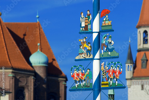 Maypole on Viktualienmarkt with musicians, dancing couple, market woman, waitress of Oktoberfest, tower of new town hall in background, Munich, Bavaria, Germany, Europe photo