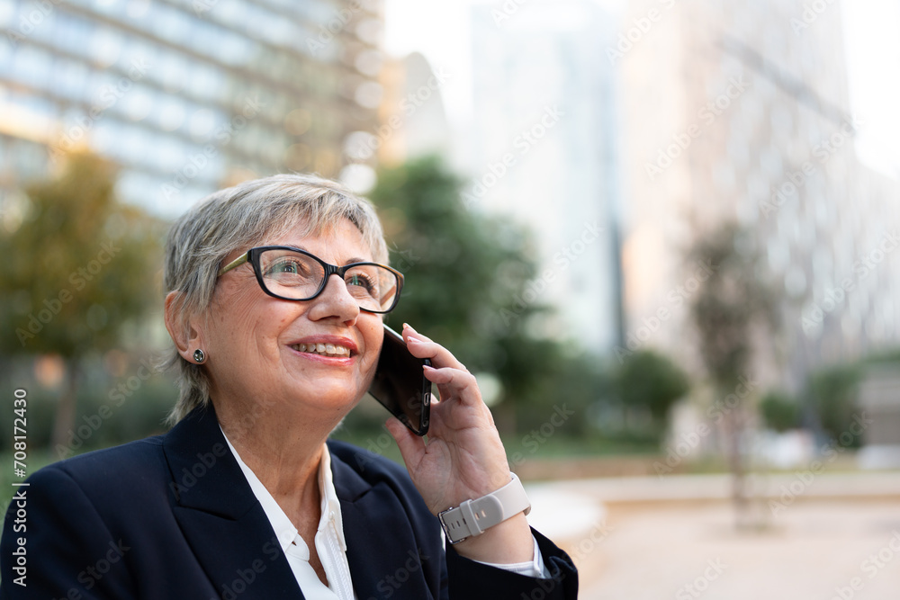 Horizontal photo with copy space of a mature smiling businesswoman talking to the mobile in the street Horizontal photo with copy space of a mature smiling businesswoman talking to the mobile in the street