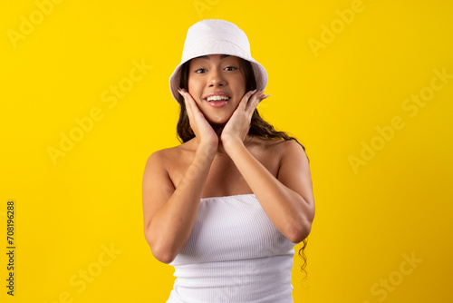 Happy young woman wearing a white dress on a yellow background