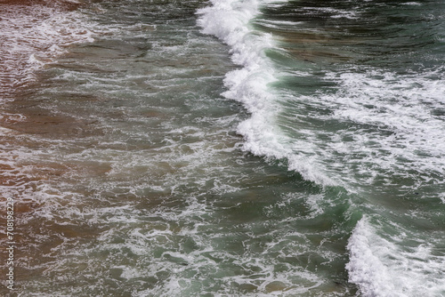 Moroccan atlantic sea waves with white foam on the sand.