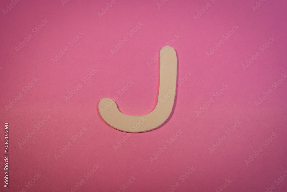 Letter J in wood on a pink background Letter J in wood on a pink background