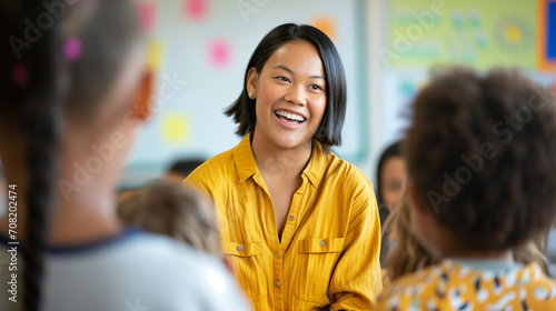 Happy young female primary school teacher teaching children, positive school education