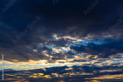 Sunset sky with dark clouds and rays of light. Nature celestial background