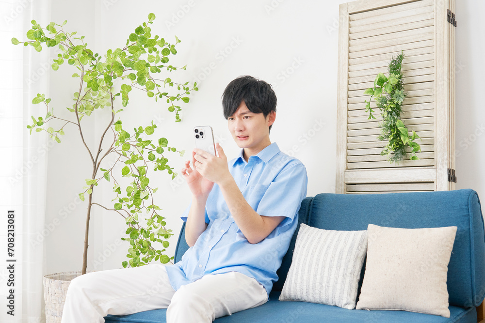 自宅でスマートフォンを使う男性 自宅でスマートフォンを使う男性