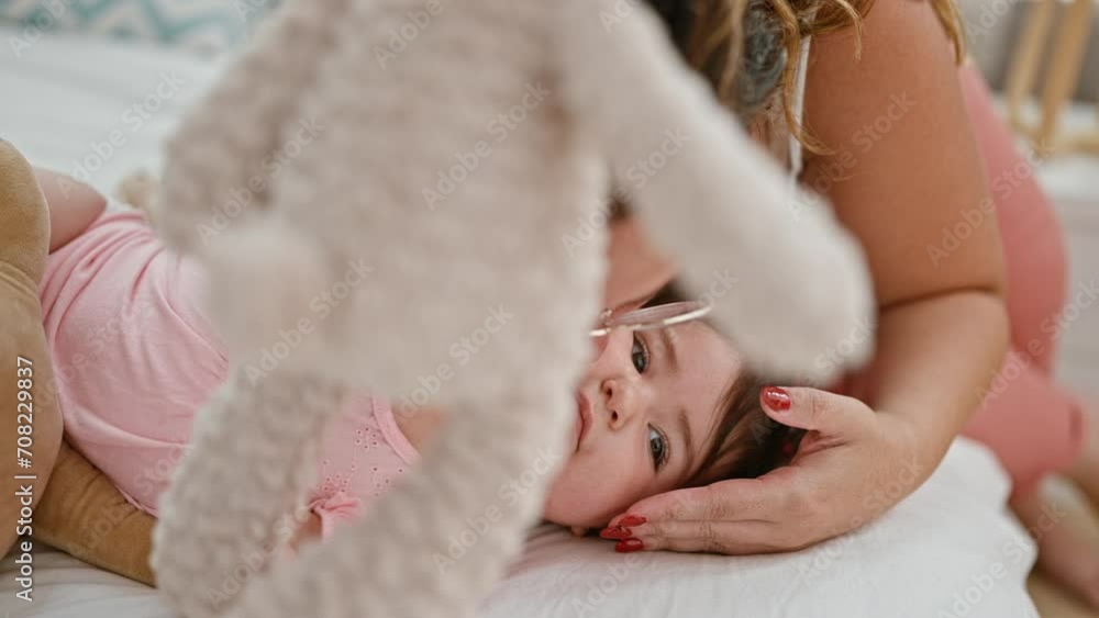 In the comfort of their home, mother and daughter share a relaxing morning in bed, smiling and expressing their love by playfully kissing teddy bear in their cozy bedroom In the comfort of their home, mother and daughter share a relaxing morning in bed, smiling and expressing their love by playfully kissing teddy bear in their cozy bedroom