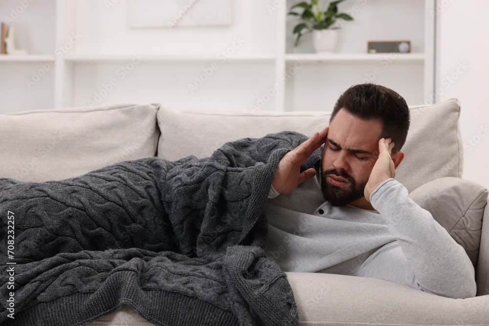 Man suffering from headache on sofa at home Man suffering from headache on sofa at home