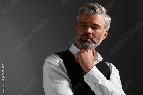 Portrait of confident man with beautiful hairstyle on dark background. Space for text