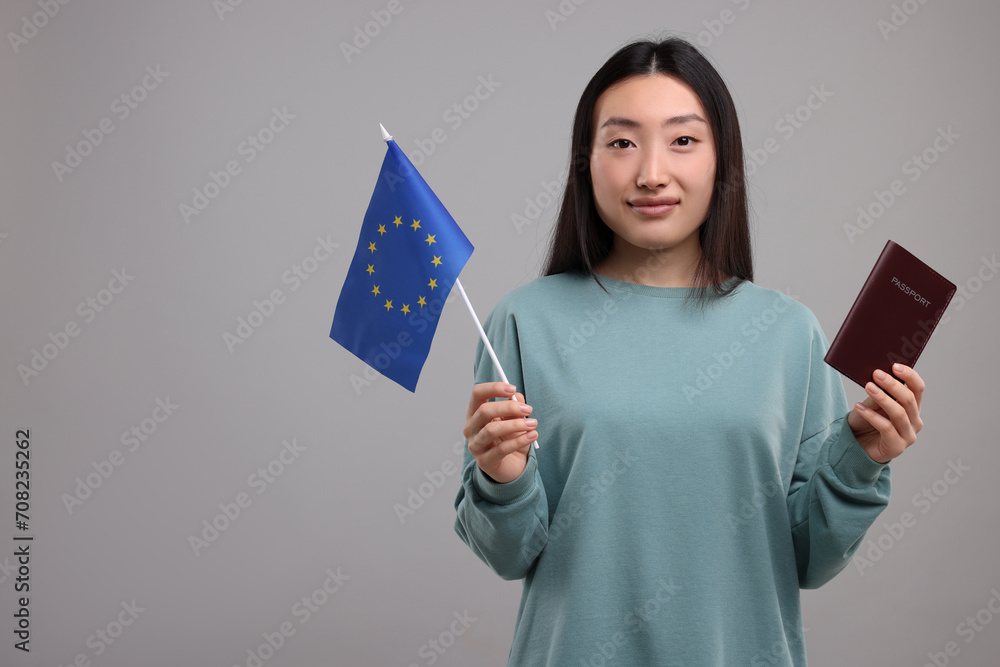 Immigration to European Union. Woman with passport and flag on grey background, space for text Immigration to European Union. Woman with passport and flag on grey background, space for text