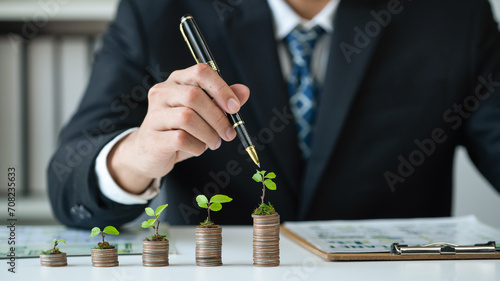 Tableau sur toile Businessman with coin stack at his office as sustainable money growth investment or eco-subsidize