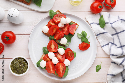 Delicious Caprese sandwiches with mozzarella, tomatoes, basil and pesto sauce on white wooden table, flat lay © New Africa