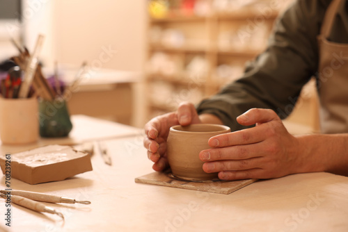 Clay crafting. Man making bowl at table indoors, closeup