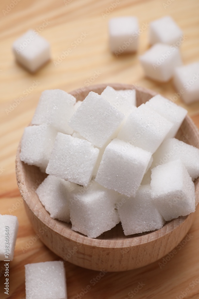 White sugar cubes in bowl on wooden table, above view White sugar cubes in bowl on wooden table, above view