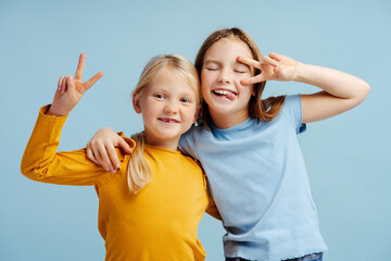 Portrait of smiling girls, cute sisters looking at camera isolated on blue background