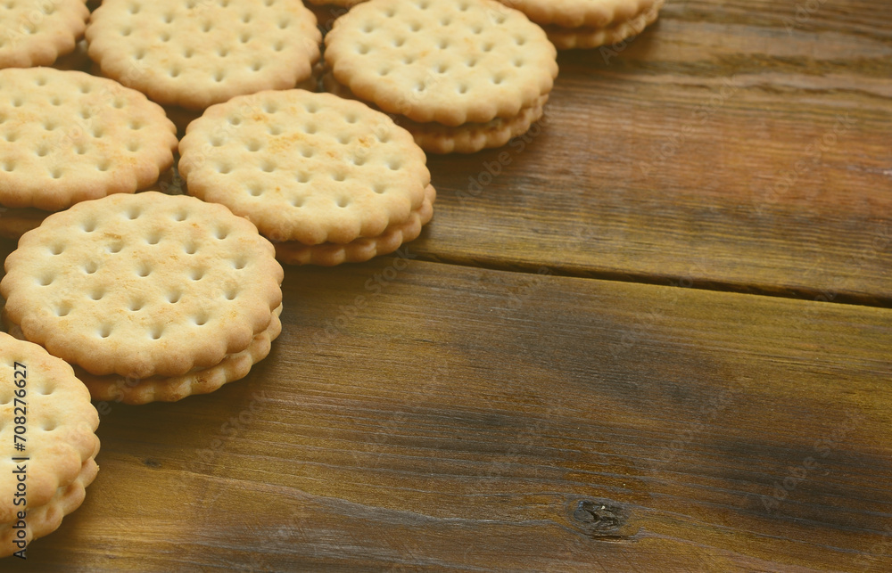 A round sandwich cookie with coconut filling lies in large quantities on a brown wooden surface. Photo of edible treats on a wooden background with copy space A round sandwich cookie with coconut filling lies in large quantities on a brown wooden surface. Photo of edible treats on a wooden background with copy space