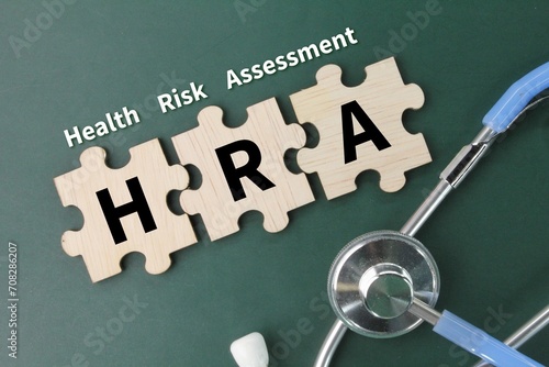 stethoscope and wooden puzzle with the letters HRA or the word Health Risk Assessment photo