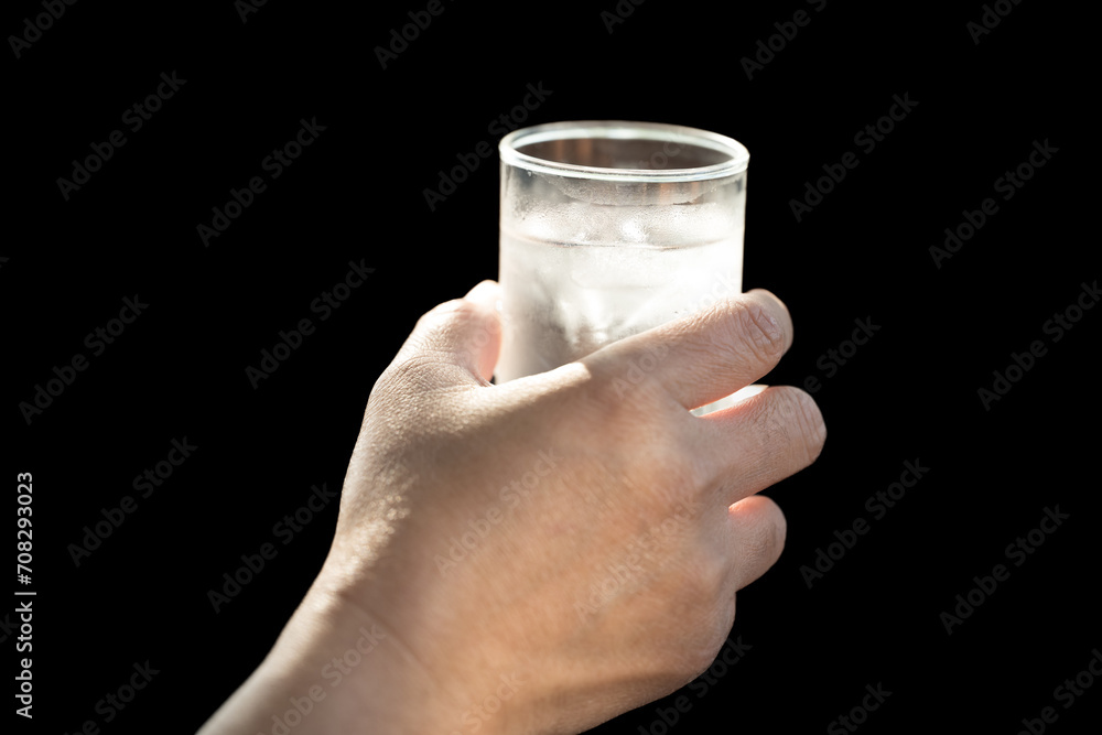 Hand holding water glass on black background.Thirsty woman holding glass drinks still water preventing dehydration.Health care food and drink concept. Hand holding water glass on black background.Thirsty woman holding glass drinks still water preventing dehydration.Health care food and drink concept.