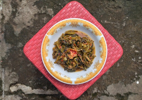 Stir-fried spicy kale with strong spices mixed with cempoka and tepus flowers served on a plate photo