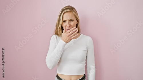 Young attractive blonde woman, standing over pink isolated background, displaying disgust. smelling intolerable stinky bad smell, holding breath with nose pinched. photo