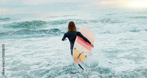 Surfing, beach and woman in water for surfboard for sports, fitness and freedom by ocean. Nature, travel and back of person running in sea for wellness on holiday, vacation and adventure for hobby