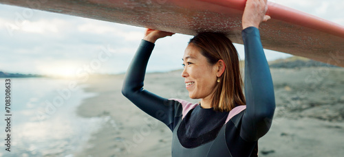 Woman, surfer with surfboard at beach and view of ocean, nature and extreme sports for fitness. Asian, athlete and smile for exercise and surfing at sunrise, workout or training for hobby outdoor