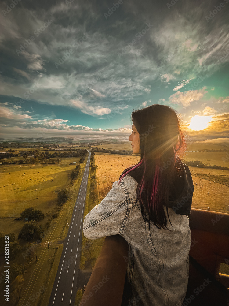Naklejka premium Photo of the young attractive woman standing in the hot air ballooning basket. Beautiful landscape top view of Yarra Valley, Melbourne, Australia. Activities, travel destinations of Melbourne