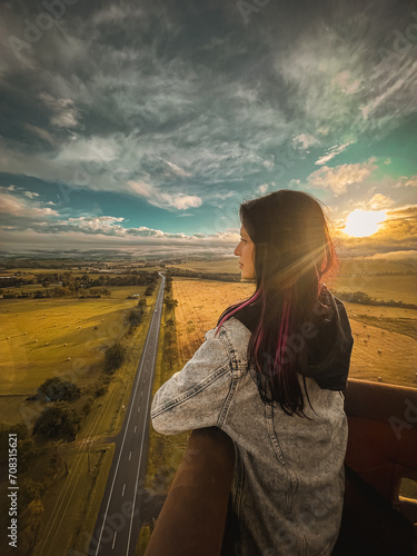 Photo of the young attractive woman standing in the hot air ballooning basket. Beautiful landscape top view of Yarra Valley, Melbourne, Australia. Activities, travel destinations of Melbourne