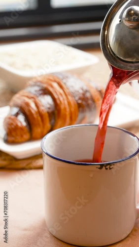 hot juice or tea is poured into a mug, steam is coming, breakfast is a croissant coffee shop