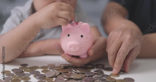 Asian mother with her little 4s son lying at home count and drop coins into piggy bank. Caring parent teaches child save money, think about future, manage personal finances, savings concept. photo