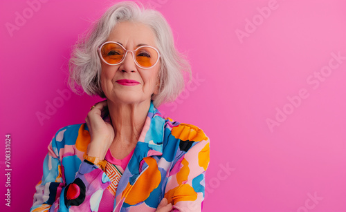 Portrait of adorable retired old woman wearing colorful fashionable clothes over pink background