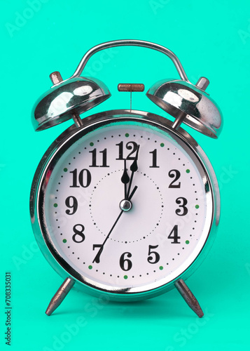 Classic vintage alarm clock isolated on green background. Retro alarm clock with twelve o'clock.