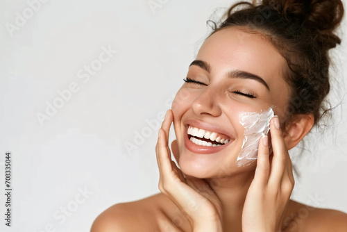 Close-up beauty portrait of a Lady with happiness applying a bit of face cream.Happy emotional daily routine, anti-aging, wrinkle reduction cosmetic theme. photo