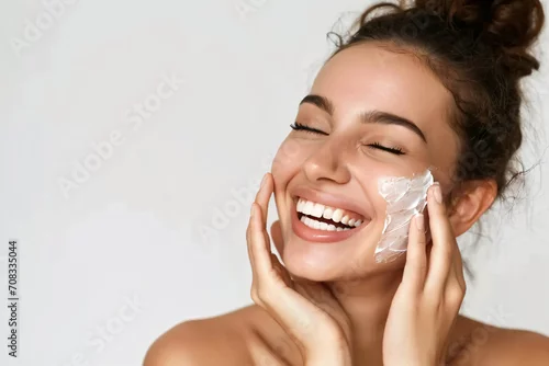 Obraz Close-up beauty portrait of a Lady with happiness applying a bit of face cream.Happy emotional daily routine, anti-aging, wrinkle reduction cosmetic theme.
