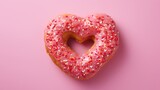 Round doughnut with sprinkles in the shape of a heart, dessert in sweet pink glaze on a pink background. Sweet dessert.