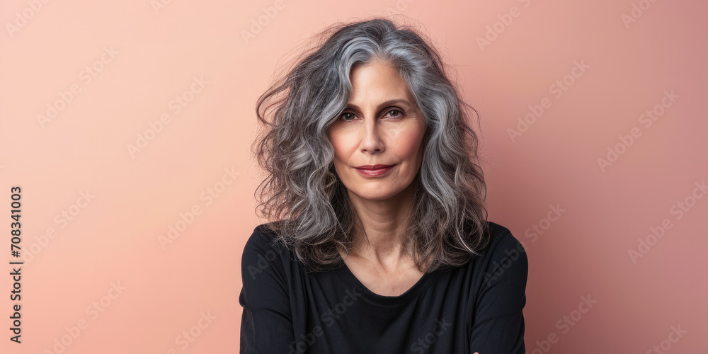 Fototapeta premium Close up of a confident middle aged woman with a peach copyspace background