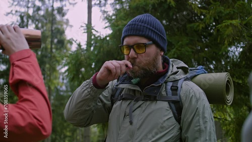 Wallpaper Mural Male tourist takes out hydration tube from backpack and starts drink water. Group of travelers stopped to rest after long expedition in beautiful forest. Nature discovery and active leisure concept. Torontodigital.ca