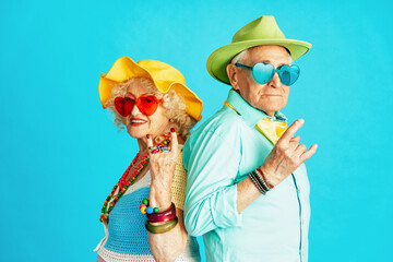 Beautiful senior old couple wearing fancy party clothes acting in studio on a colored background. Conceptual image about third age and seniority, old people feeling young inside.