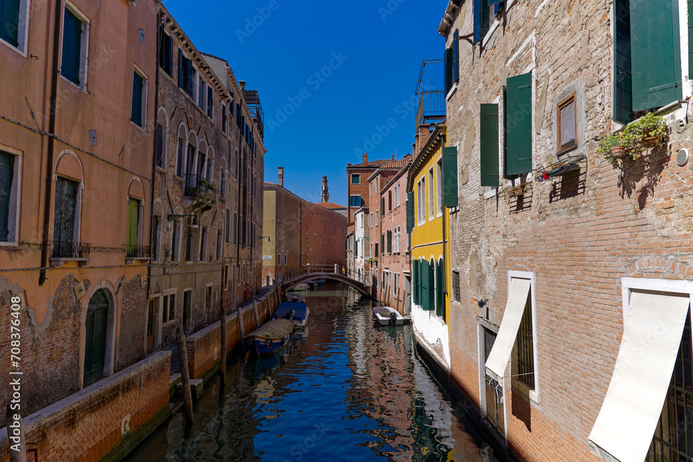Old town of City of Venice with canal and moored boats and beautiful reflections in water on a sunny summer day. Photo taken August 7th, 2023, Venice, Italy.
