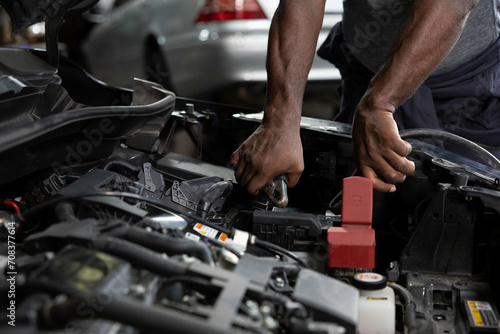 close up mechanic worker hands holding battery cable for jumping battery of a car in automobile repair shop photo