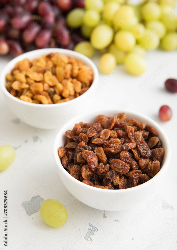 Bowls of green and red dark raisins with ripe raw grapes on light background.Macro. Bowls of green and red dark raisins with ripe raw grapes on light background.Macro.