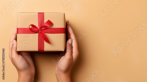 Captivating First Person View: Young Woman's Hands Gracefully Holding Kraft Paper Giftbox on Isolated Beige Background - Festive Celebration Concept with Copy Space